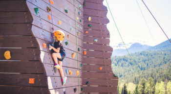 A little girl excelling at climbing the climbing wall.