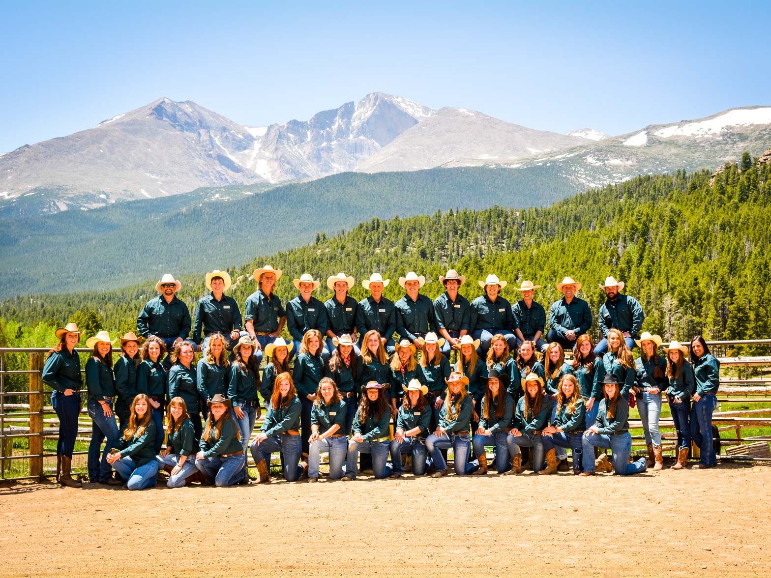 Group photo of young camp staff members in front of a beautiful mountainous landscape.